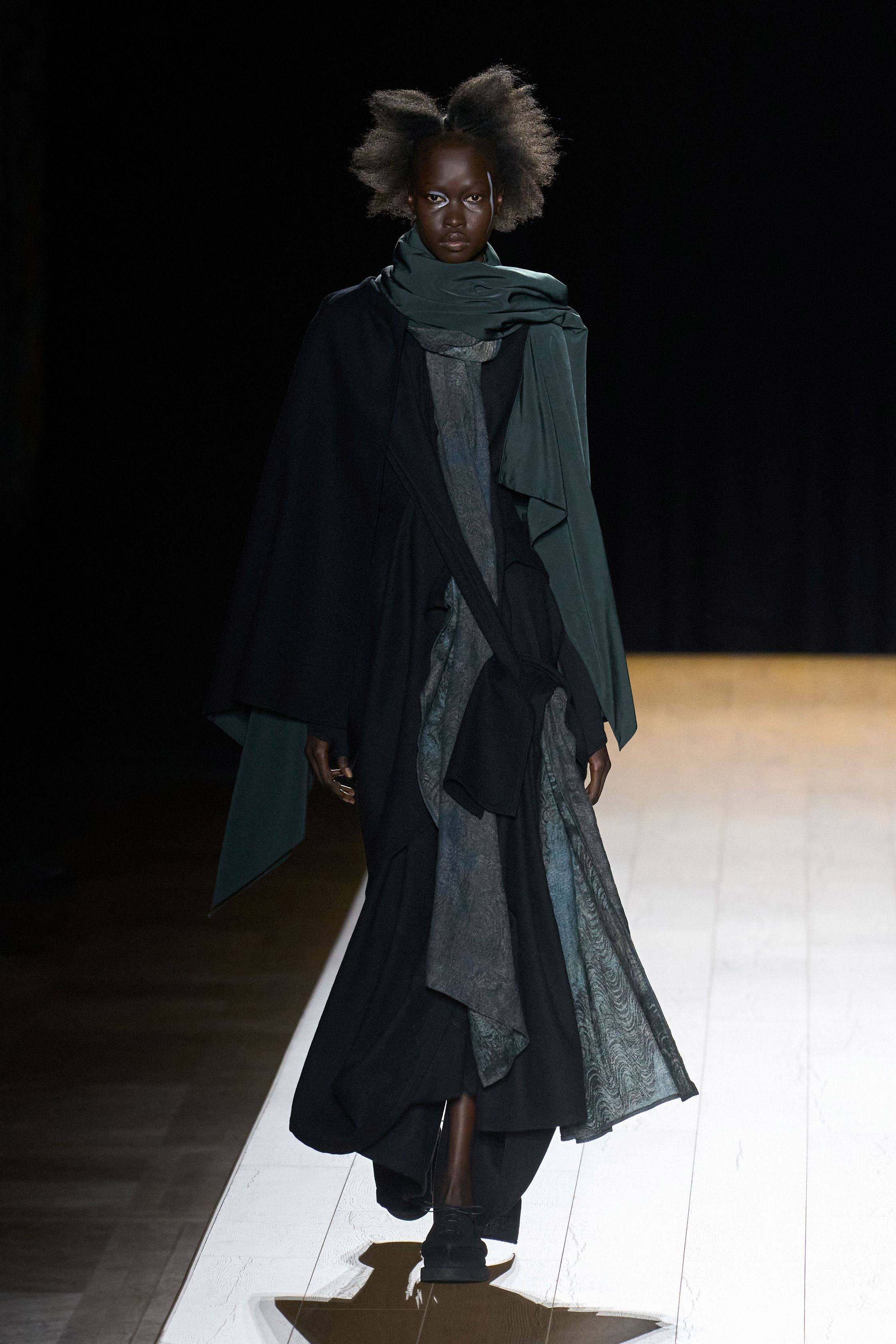 Yohji Yamamoto 本季依然延续标志性的黑色哲学：宽松层叠轮廓、和服式结构与手工拼接面料形成一种诗意而深沉的东方美学。夸张头饰与飘逸衣摆让整场秀像一场黑色戏剧，既神秘又极具艺术感-顽石频道趋势研究